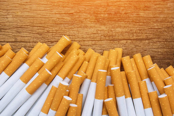 Een bovenaanzicht beeld van verschillende commercieel gemaakte sigaretten. stapel sigaret op houten. of niet-roken campagne concept - Foto, afbeelding