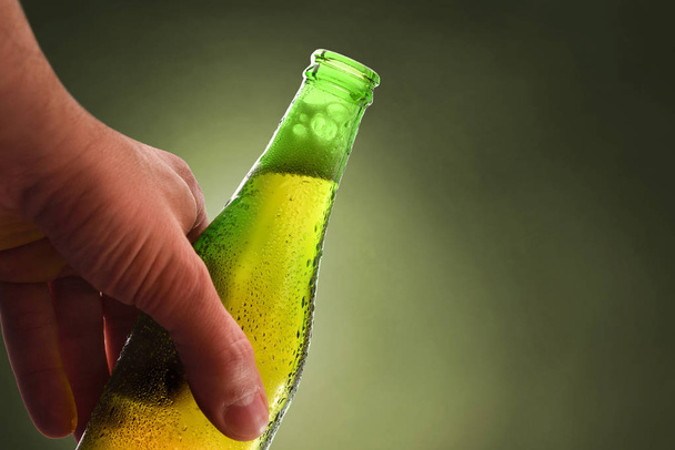 Láhev s rukou plnou otevřeného alkoholického nápoje zelený backgroun - Fotografie, Obrázek