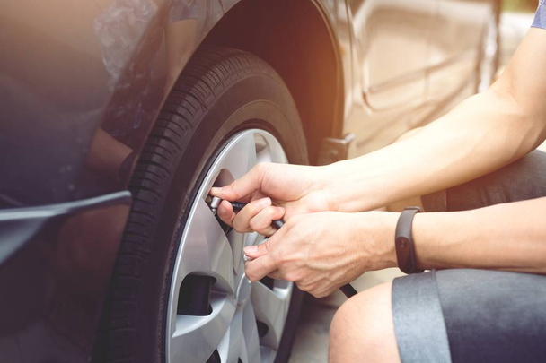 クローズアップハンドマン駐車場は、外出先で安全運転のためにタイヤが空気を満たすためのチェック. - 写真・画像