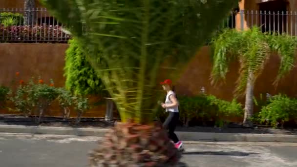 Woman runs down the street among the palm trees. Healthy active lifestyle - Imágenes, Vídeo
