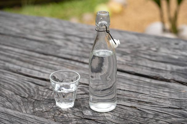 Bouteille et verre avec eau sur la table en bois
 - Photo, image
