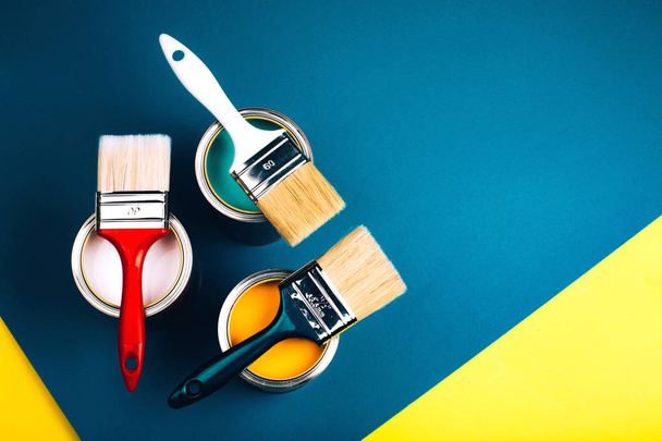 Three open cans with brushes on them on yellow and blue background. - Foto, Imagem