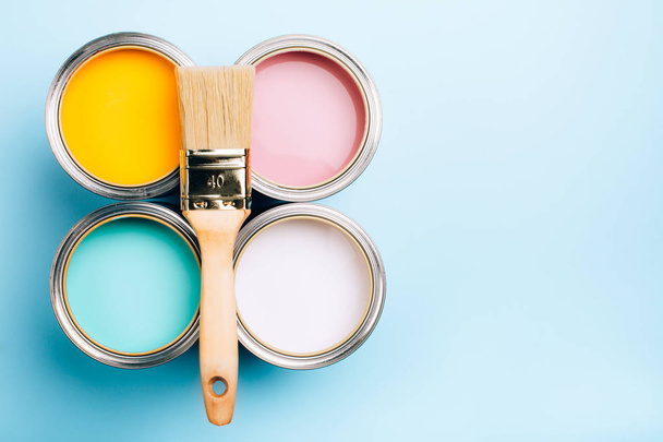 Brush with wooden handle on open cans on blue pastel background. - Foto, afbeelding
