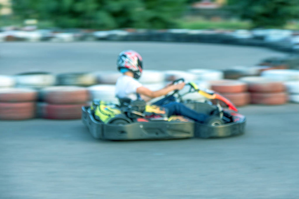 Strong motion blur karting. The picture is out of focus. Racers on races on special safe high-speed tracks limited by car tires. Attraction High-speed ride in carts. Sport karting entertainment - Foto, Imagen
