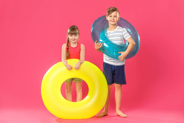 niedliche kleine Kinder mit aufblasbaren Ringen auf farbigem Hintergrund - Foto, Bild