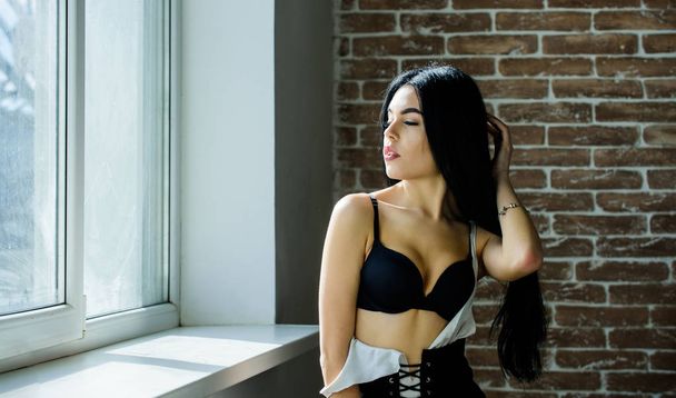 Passionate mysterious lover. Enjoying morning sunlight. Sensual girl sexy breasts relaxing near windowsill. Attractive female lingerie just relaxing at home. Fan of role games. Enjoying her beauty - 写真・画像