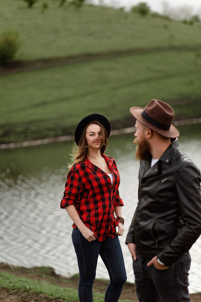 a man and a woman walk on green hills ranching along a lake - Foto, Imagen