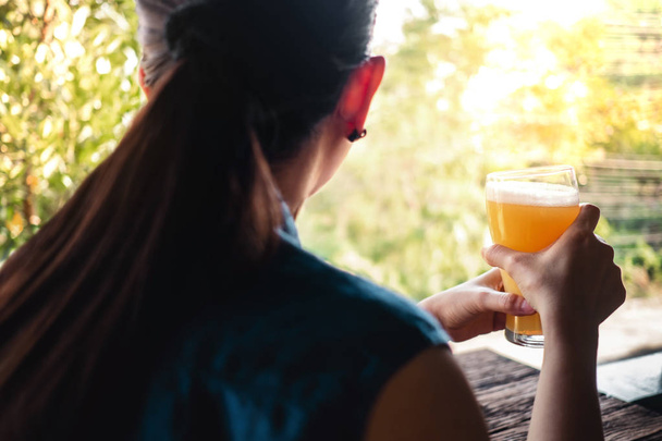 Mujer relajándose con un vaso de cerveza en el balcón en verano
 - Foto, Imagen