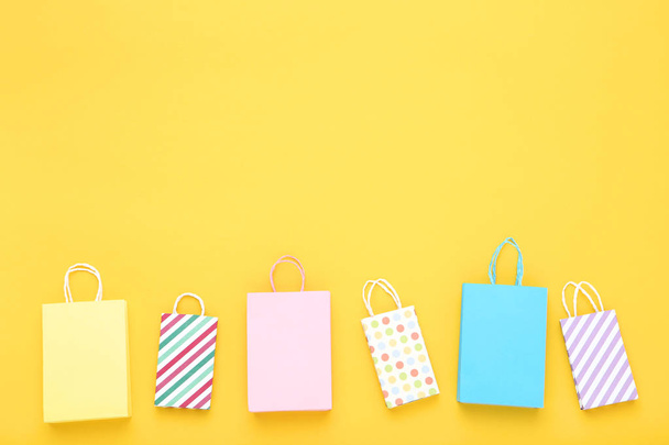 Small paper shopping bags on yellow background - Valokuva, kuva