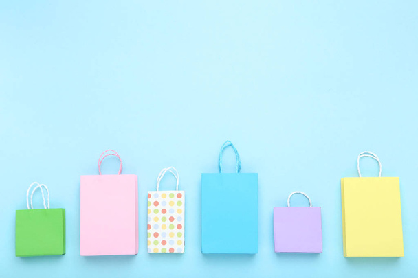 Small paper shopping bags on blue background - Foto, Imagem