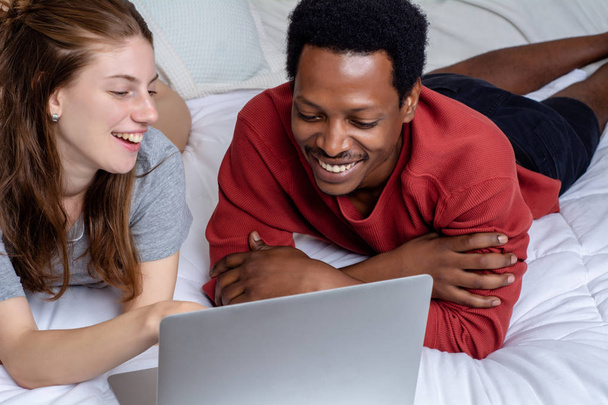 Young couple using laptop in a bed at home. - Photo, image