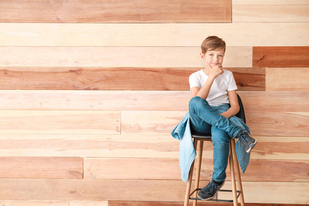 Κομψό αγόρι σε ρούχα τζιν κοντά σε ξύλινο τοίχο - Φωτογραφία, εικόνα