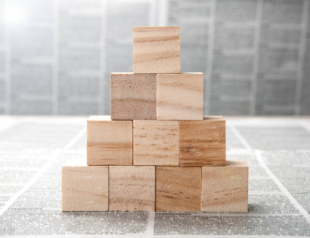 квадратные деревянные блоки в виде пирамиды на газетах
 - Фото, изображение