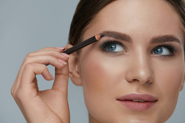 Beauty makeup. Woman shaping eyebrow with brow pencil closeup - Photo, Image