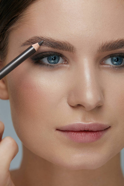 Beauty makeup. Woman shaping eyebrow with brow pencil closeup - Фото, зображення
