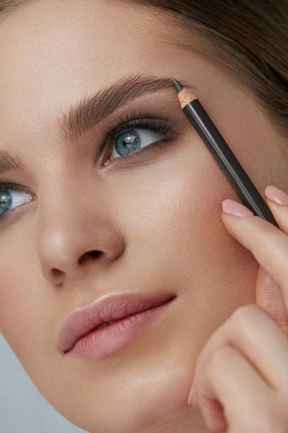 Eyebrow makeup. Beauty model shaping brows with brow pencil - Фото, зображення