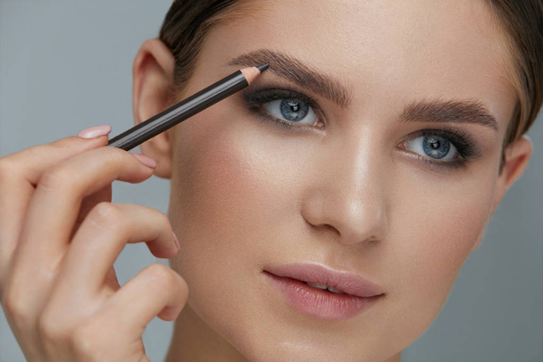 Beauty makeup. Woman shaping eyebrow with brow pencil closeup - Photo, Image