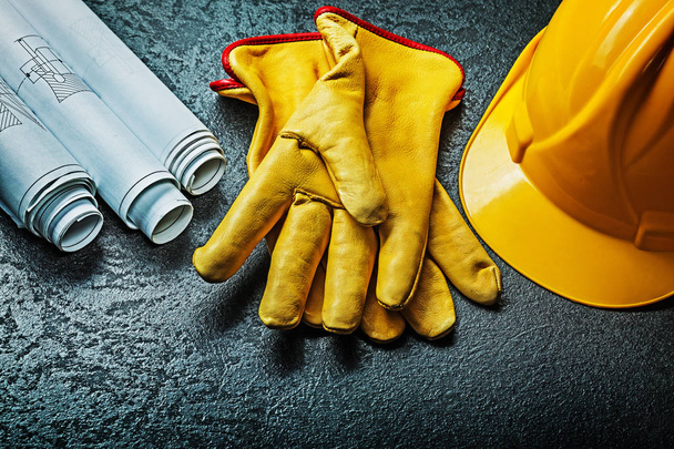 working gloves with yellow helmet and rolled blueprints - 写真・画像