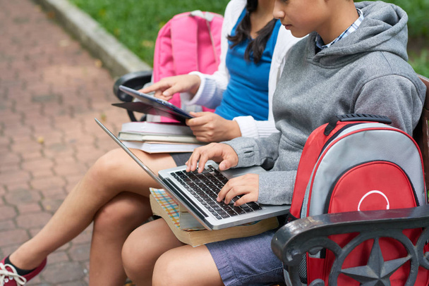 Les enfants se reposent sur un banc dans le parc avec des gadgets après l'école
 - Photo, image