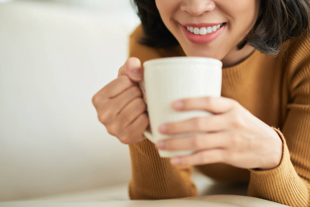 mujer sonriente con taza de té blanco acostado en la cama y relajante, imagen recortada
  - Foto, imagen