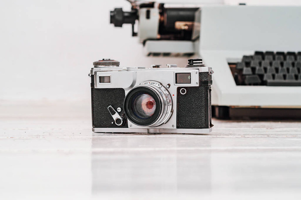 Old film camera on white plank background. Typewriter on the bac - Photo, Image