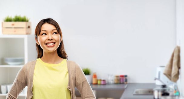 happy asian woman looking up at kitchen - Foto, imagen