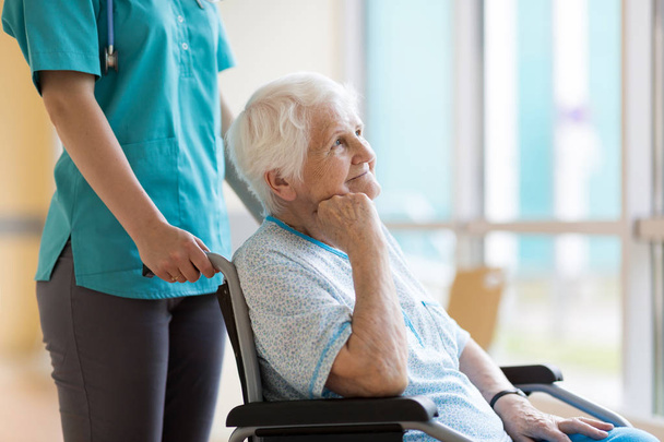 Mujer mayor en silla de ruedas con enfermera en el hospital
 - Foto, imagen