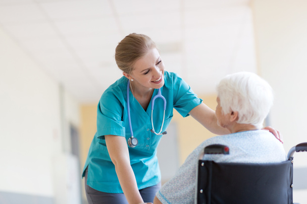 Senior woman in wheelchair with nurse in hospital - Foto, imagen