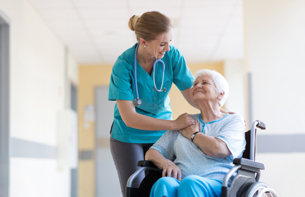 Senior woman in wheelchair with nurse in hospital - Foto, imagen