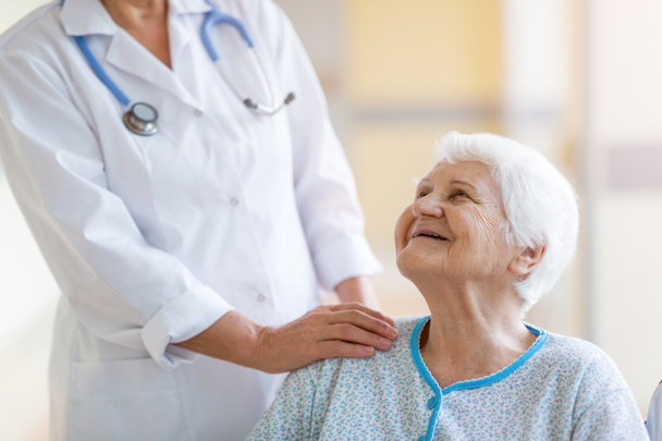 Starší žena na kolečkovém křesle s doktorem v nemocnici - Fotografie, Obrázek