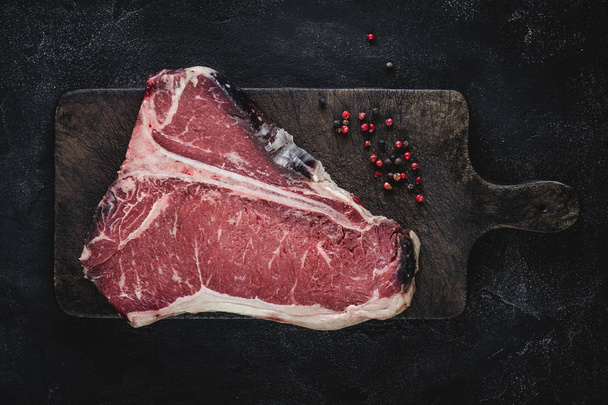 Raw T-bone Steak Dry Aged for Grill or BBQ on Vintage Cutting Board - Photo, image