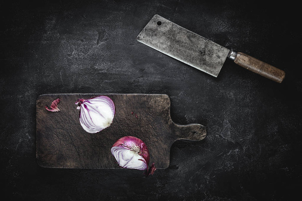 Cebolla roja a la mitad en el tablero de corte vintage con cuchilla de carne
 - Foto, imagen
