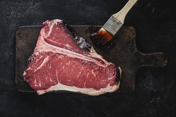 T-bone Steak Raw Dry Aged Beef on Vintage Cutting Board - Foto, afbeelding