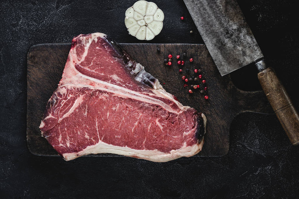 T-bone Steak carne cruda seca envejecida en la tabla de corte Vintage
 - Foto, imagen