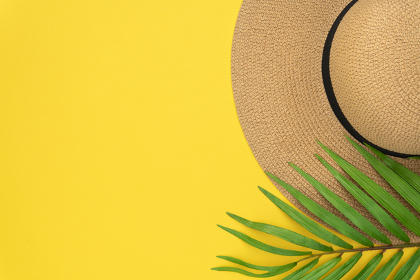 Nyári vakáció, nyaralás, utazás, idegenforgalmi koncepció. V. szalma kalap, trópusi Pálma levelek fehér sárga papír háttérben. A nyári koncepció felső nézete szóközzel a szöveghez - Fotó, kép