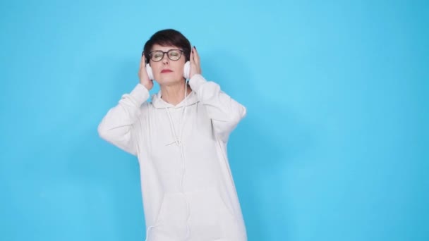 Amor por el concepto musical. Mujer madura transmite música en auriculares sobre un fondo azul
 - Imágenes, Vídeo