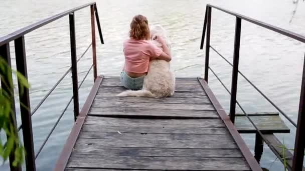 Woman sitting n the pontoon with her labrador - Footage, Video