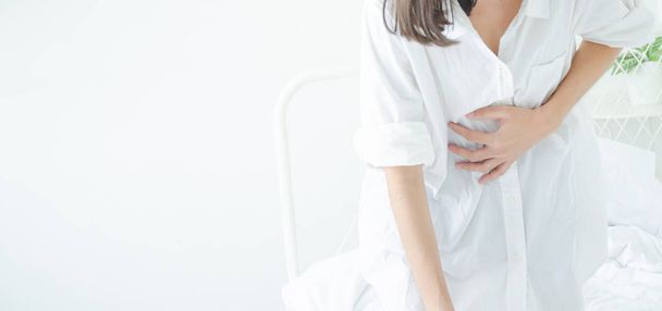 Aziatisch meisje heeft buikpijn. Wanneer is de menstruatie. Vang zijn maag. Vrouwen hebben blaas pijn. Niet focussen op objecten - Foto, afbeelding