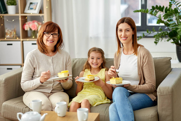 mother, daughter and grandmother eating cake - Foto, immagini