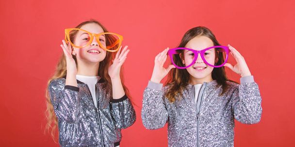 Happy childhood. Sincere cheerful kids share happiness and love. Joyful and cheerful. Sisterhood concept. Friendly relations siblings. Girls funny big eyeglasses cheerful smile. Birthday party - 写真・画像