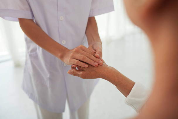 Крупный план врача, трогающего руку пожилого пациента, чтобы успокоить и поддержать ее
 - Фото, изображение