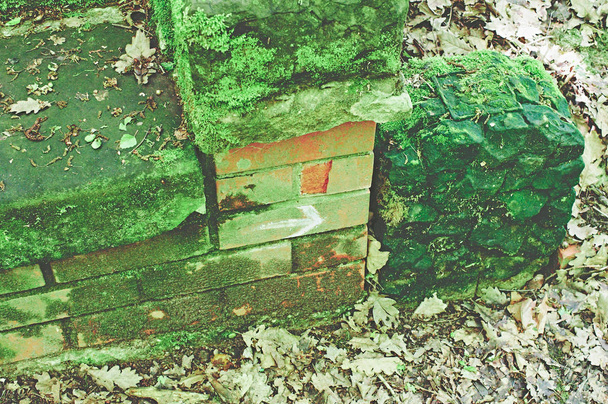 Pierre tombale cassée avec dommages sur un cimetière en vert
 - Photo, image