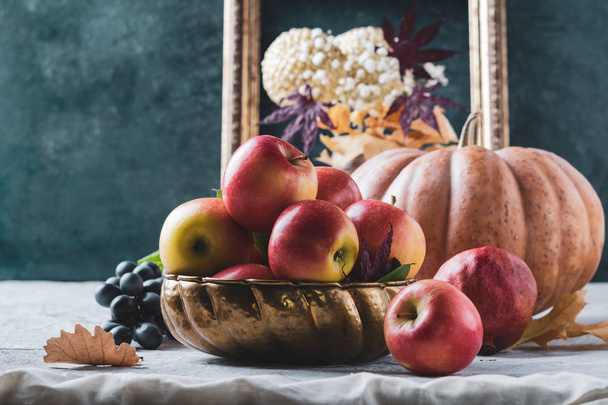 Cosecha otoñal y fondo de acción de gracias. Varias frutas, manzanas, uva en cuenco de metal viejo y hojas de otoño
 - Foto, Imagen