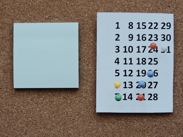 Planung eines Projekt-close-up.thumbtack im Kalenderkonzept für geschäftige Arbeitsbereiche. Geschäftstreffen, Reiseplanung oder Projektarbeit und Erinnerungskonzept. Schreibtischkalender mit Tagen und Terminen. Ansicht von oben - Foto, Bild