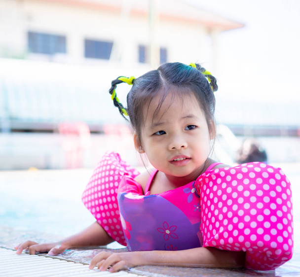 маленькая азиатская девочка с надувными рукавами плавает в какашках
 - Фото, изображение