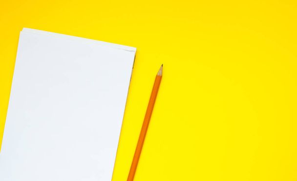 Iskolai notebook ceruzával sárga háttérrel. Üres jegyzetfüzet oldal részére bemenet a szöveg középen. Felülnézet, üzleti, irodai kellékek vagy oktatási koncepció. Iskolai irodaszerek. minimális stílus.  - Fotó, kép