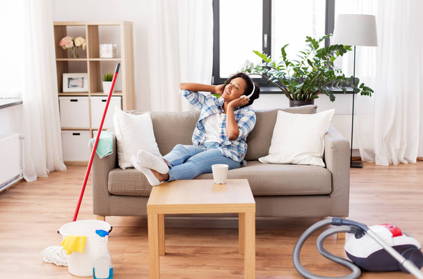 vrouw in hoofdtelefoon rusten na het schoonmaken van huis - Foto, afbeelding