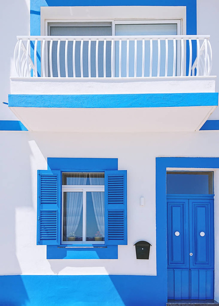 Fachada frontal de edificio residencial con puerta y ventana azul
 - Foto, imagen