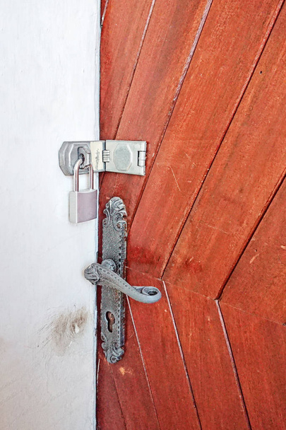 Закрыть обзор навесного замка на деревянной входной двери и дверной ручке
. - Фото, изображение