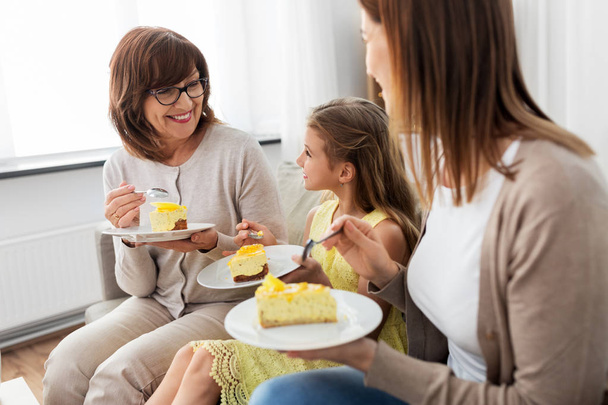 mother, daughter and grandmother eating cake - Zdjęcie, obraz